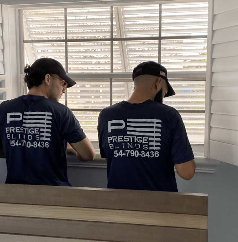 Two men in matching shirts and hats looking at a window.