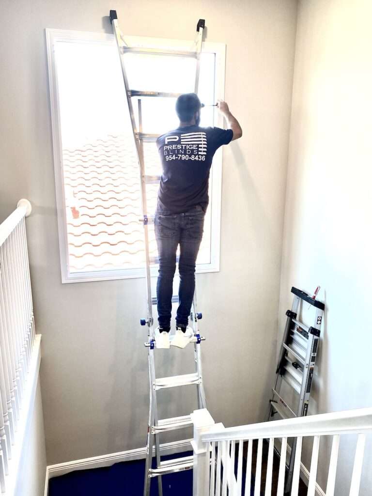 man installing blinds on window