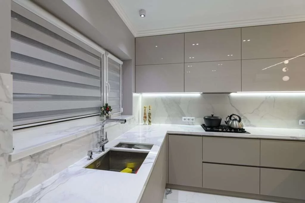 A kitchen with white counters and gray cabinets.