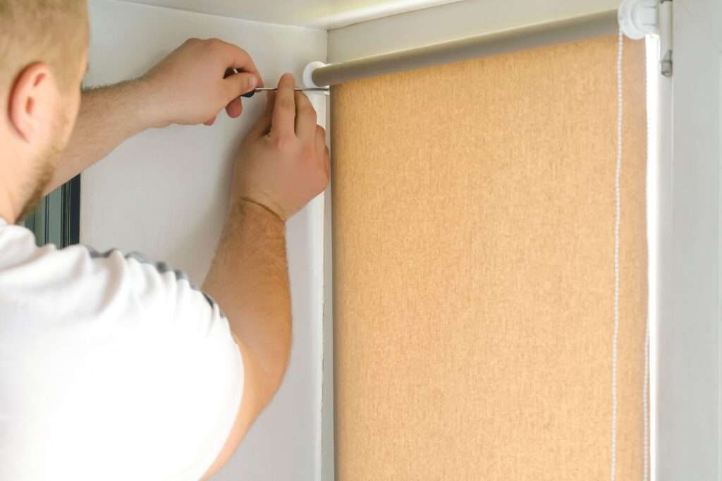 man male worker hands installing attaching mounting bracket on roller blinds,shades,plastic window